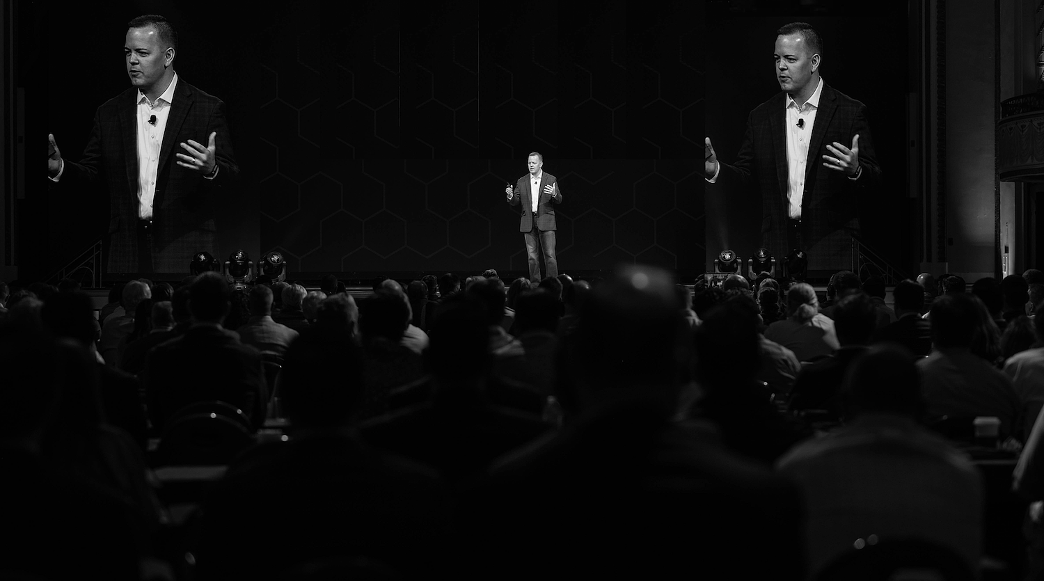 Aaron Klein speaking to an audience from a stage.